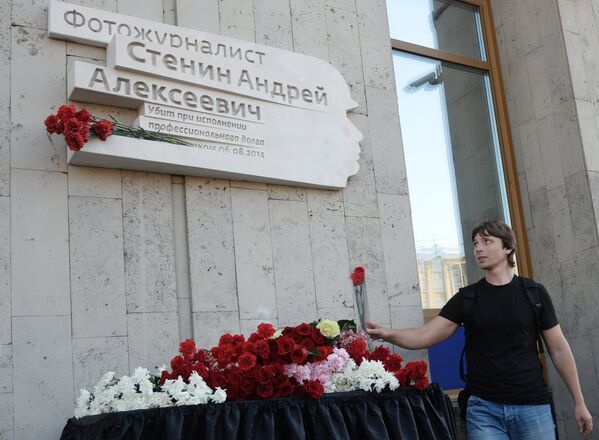 Um jornalista coloca flores perto da placa em homenagem ao fotojornalista de Rossiya Segodnya Andrei Stenin, morto em 6 de agosto de 2014 na Ucrânia no desempenho de sua atividade profissional - Sputnik Brasil