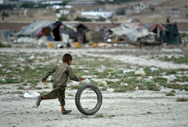 Um menino afegão brinca com um pneu perto da sua tenda nos arredores de Kabul. 2 de agosto de 2015 - Sputnik Brasil