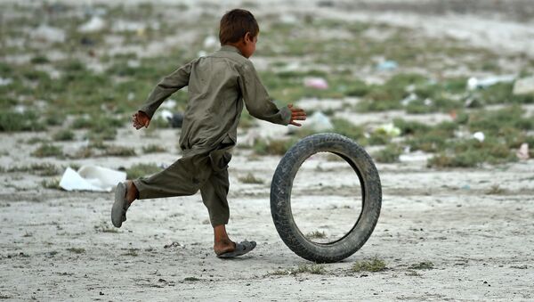 Um menino afegão de nômade Kochi brinca com o pneu perto da sua tenda nos arredores de Kabul. 2 de agosto de 2015 - Sputnik Brasil