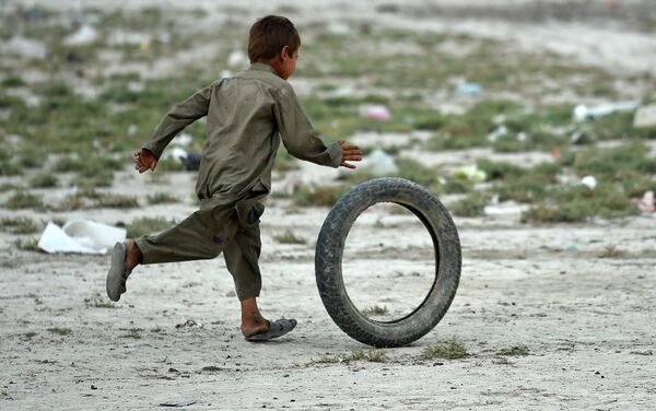 Um menino afegão de nômade Kochi brinca com o pneu perto da sua tenda nos arredores de Kabul. 2 de agosto de 2015 - Sputnik Brasil