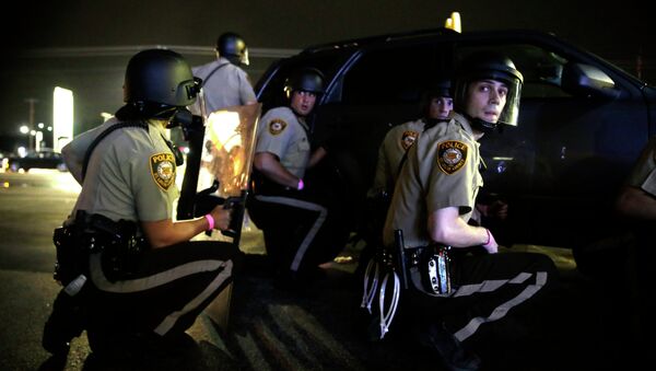 Policiais de Ferguson se escondem atrás de veículo durante manifestações um ano após a execução do jovem negro Michael Brown - Sputnik Brasil