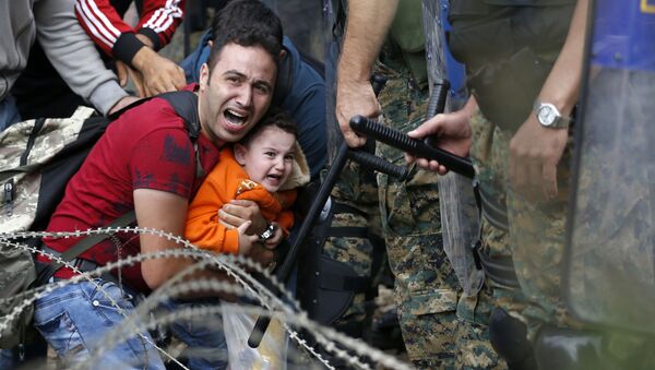 Imigrante com criança durante conflito entre imigrantes e polícia da Macedônia - Sputnik Brasil
