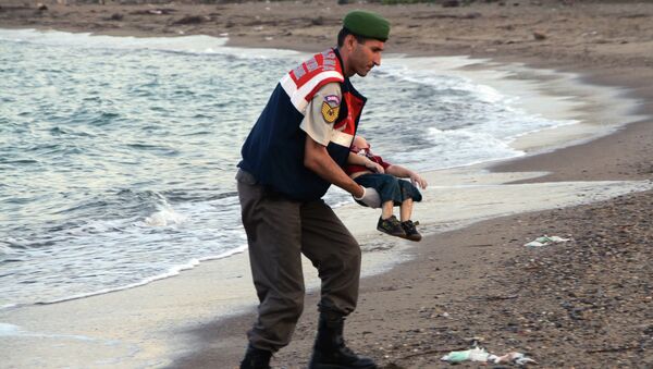 A paramilitary police officer carries the lifeless body of an unidentified migrant child, lifting it from the sea shore, near the Turkish resort of Bodrum, Turkey, early Wednesday, Sept. 2, 2015. - Sputnik Brasil