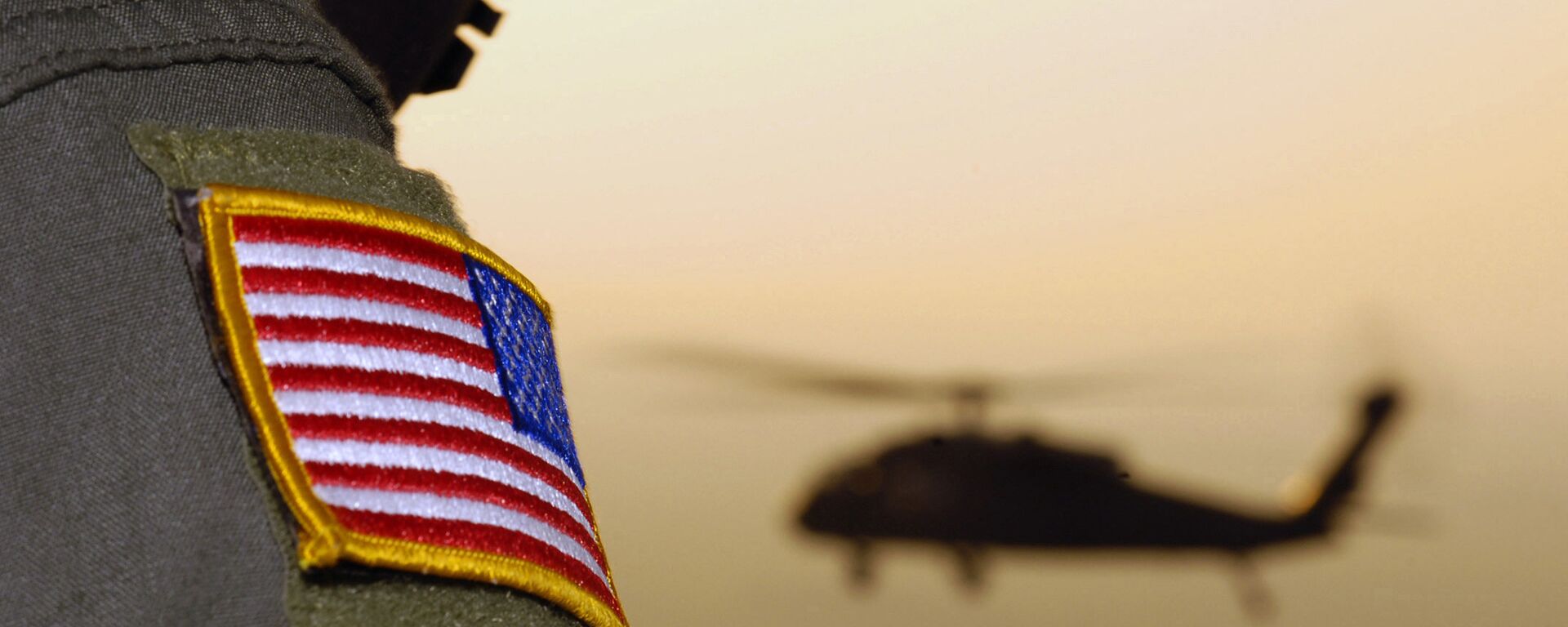 Bandeira americana de oficial do exército americano com um helicóptero UH-60A Black Hawk ao fundo - Sputnik Brasil, 1920, 27.05.2022