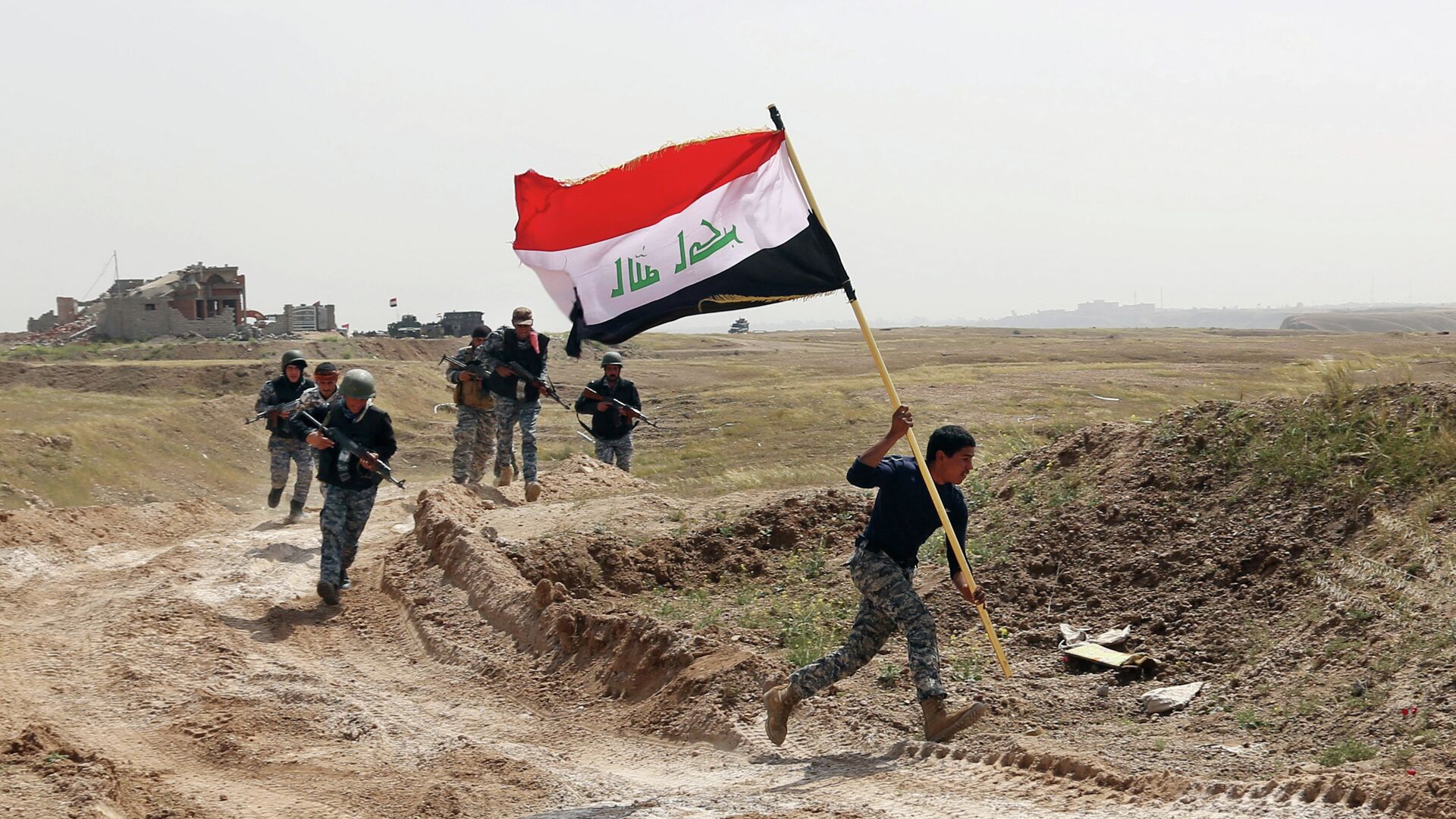 Integrante das forças de segurança do Iraque corre com a bandeira do país após país cercar Tikrit, tomada pelo Estado Islâmico - Sputnik Brasil, 1920, 26.01.2024