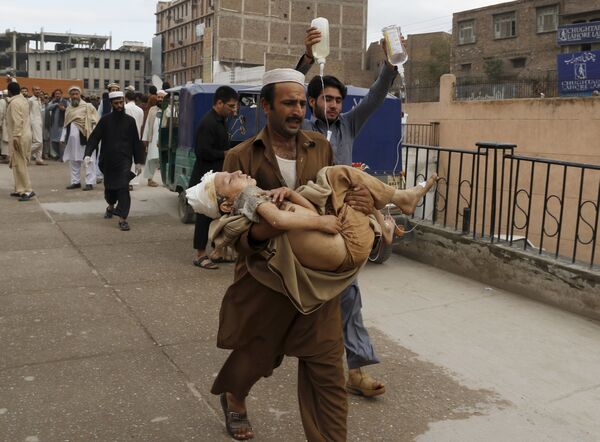 Um homem carrega uma criança ferida durante o terremoto no Paquistão - Sputnik Brasil