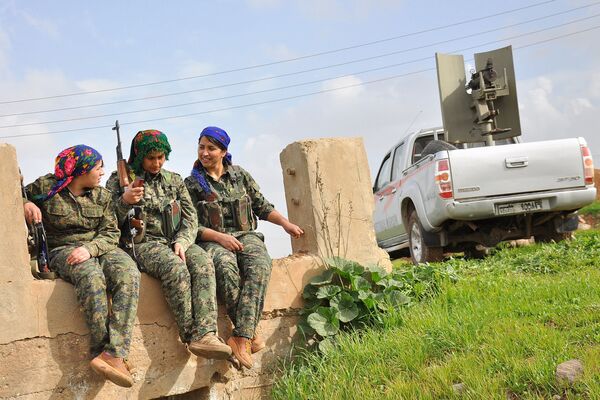 Milicianas curdas da Unidades de Proteção das Mulheres (YPJ) sentam-se ao lado de um carro com uma metralhadora pesada. Um campo de treinamento em al-Qahtaniyah, perto da fronteira sírio-turca. - Sputnik Brasil