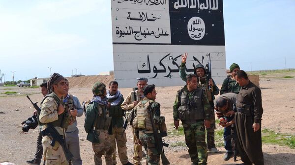 Combatentes peshmerga do Curdistão iraquiano ao lado de uma placa do Daesh (Estado Islâmico) - Sputnik Brasil