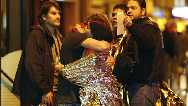 As pessoas se abraçam antes de serem evacuadas de autocarro, perto da sala dos concertos Bataclan, Paris, 14 de novembro, 2015 - Sputnik Brasil