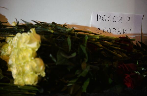 Rússia exprime seus pesames, diz a inscrição, em russo, juntada a flores na entrada da embaixada da França em Moscou - Sputnik Brasil