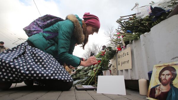 Uma jovem deposita flores na entrada da embaixada da França em Moscou neste sábado - Sputnik Brasil