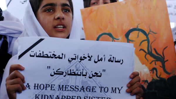 Menina yazidi empunha um cartaz que diz Mensagem de esperança para a minha irmã: estamos à tua espera durante o protesto perto do escritório da ONU em Arbil, capital da região autónoma de Curdistão, Iraque, 2 de agosto de 2015 - Sputnik Brasil