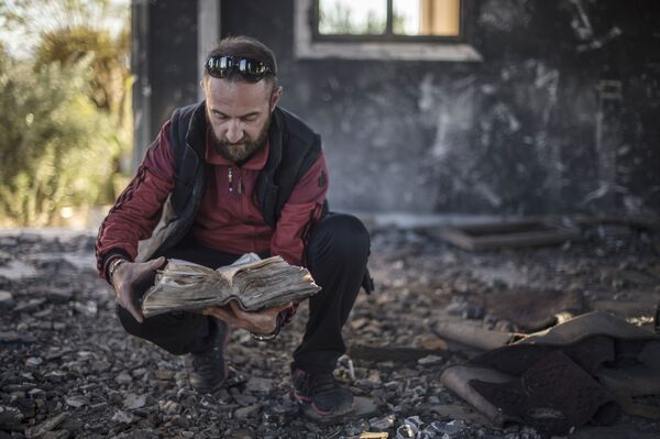 Morador encontra a Bíblia em ruínas de um vilarejo cristão destruído pelo Daesh na província de Al-Hasaka, nordeste da Síria - Sputnik Brasil