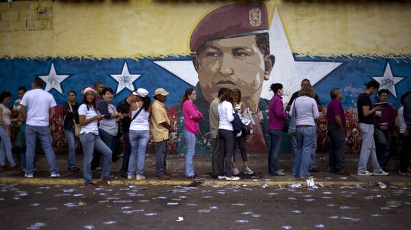Venezuelanos em fila para participar de eleições em seu país tendo ao fundo imagem de Hugo Chávez pintada em muro - Sputnik Brasil