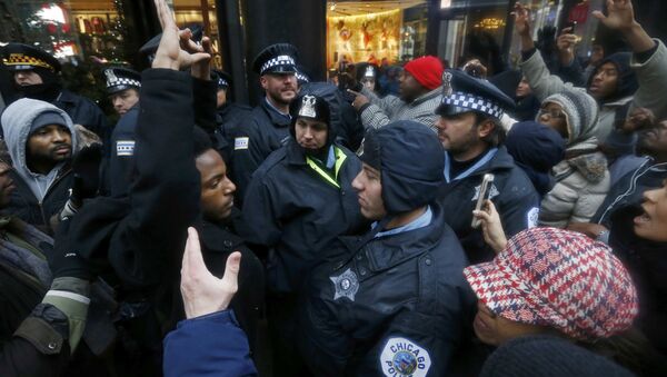 Demonstators hold their hands up in front of Chicago Police officers during protest of last year's shooting death of black teenager Laquan McDonald by a white policeman and the city's handling of the case in the downtown shopping district of Chicago, Illinois, November 27, 2015 - Sputnik Brasil