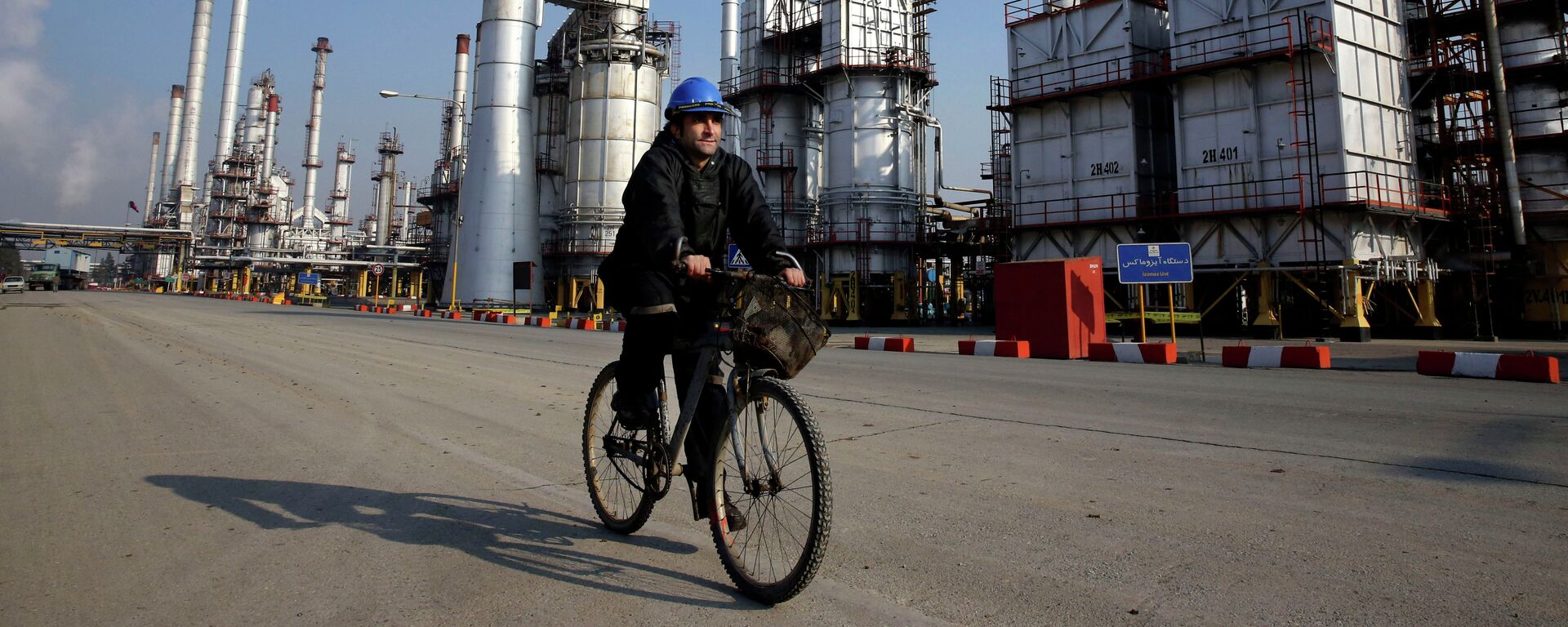 Funcionário do setor petrolífero iraniano vai de bicicleta  perto da refinaria petrolífera no sul de Teerã, Irã  - Sputnik Brasil, 1920, 29.09.2022