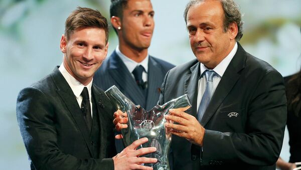 Barcelona's Lionel Messi (L) receives from UEFA President Michel Platini the Best Player UEFA 2015 Award during the draw ceremony for the 2015/2016 Champions League Cup soccer competition at Monaco's Grimaldi Forum while Cristiano Ronaldo (C) looks on in Monte Carlo August 27, 2015 - Sputnik Brasil