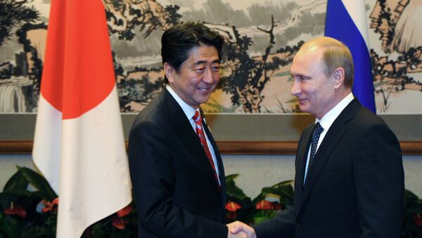 O primeiro-ministro japonês Shindzo Abe e o presidente russo Vladimir Putin apertam as mãos durante o fórum de Cooperação Econômica Ásia-Pacífico em Pequim, China, 4 de novembro de 2014 - Sputnik Brasil