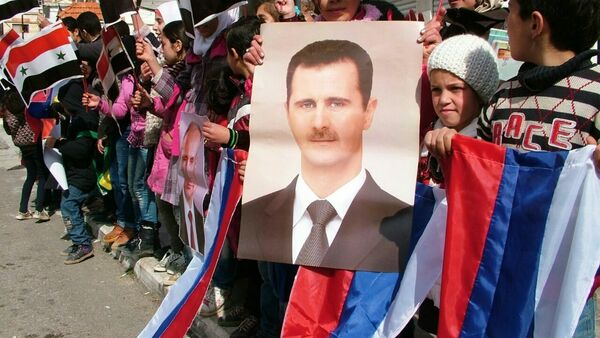 Aguardando a distribuição da ajuda humanitária russa, jovens fazem fila e mostram cartazes com retratos dos presidentes sírio e russo e bandeiras desses países - Sputnik Brasil