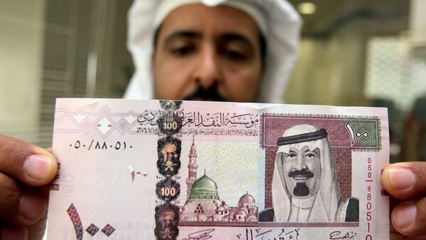 Bancário saudita mostra cédula com o retrato do rei Abdullah bin Abdul Aziz al-Saud em um banco de Riad - Sputnik Brasil