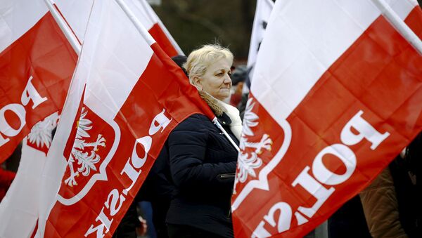 Mulher carrega bandeiras da Polônia durante protesto exigindo respeito à Constituição por parte do novo governo do país, Varsóvia, 12 de março de 2016 - Sputnik Brasil
