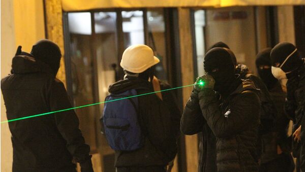 Um manifestante em máscara aponta algo com laser. Foto de arquivo (14 de fevereiro, 2016) - Sputnik Brasil