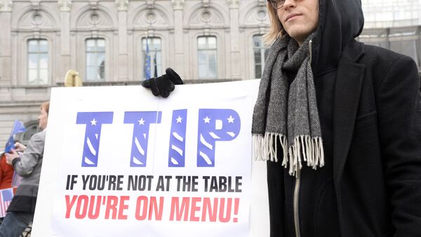 Um manifestante mostra o seu cartaz dizendo, em inglês: TTIP: se você não está à mesa, você está no cardápio durante um ato na entrada do Parlamento Europeu em 24 de fevereiro de 2016 - Sputnik Brasil