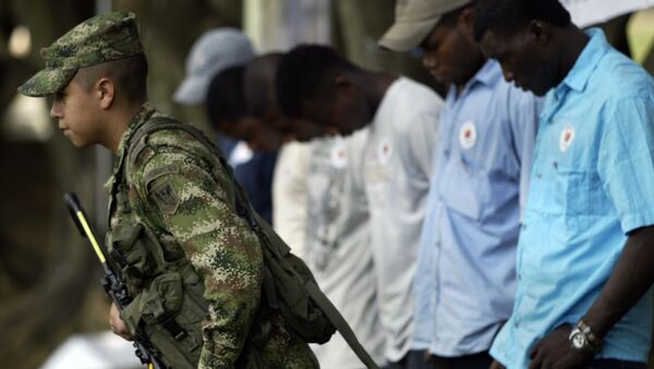 Um soldado do exército colombiano passa na frente de uma fila de guerrilheiros das FARC e do ELN - Sputnik Brasil