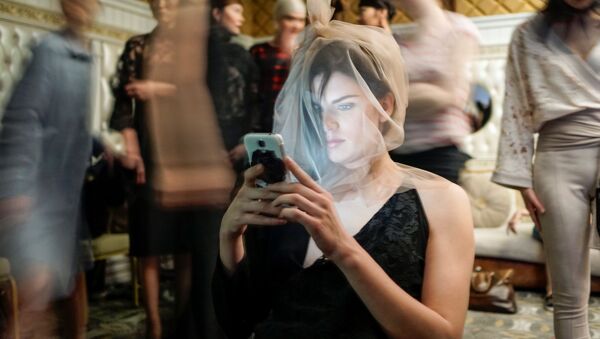 Modelo sentada com celular nos bastidores na Semana da Moda, na cidade de Almaty, Cazaquistão - Sputnik Brasil