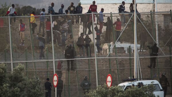 Sub-Saharan migrants sit on a metal fence that divides Morocco and the Spanish enclave of Melilla - Sputnik Brasil