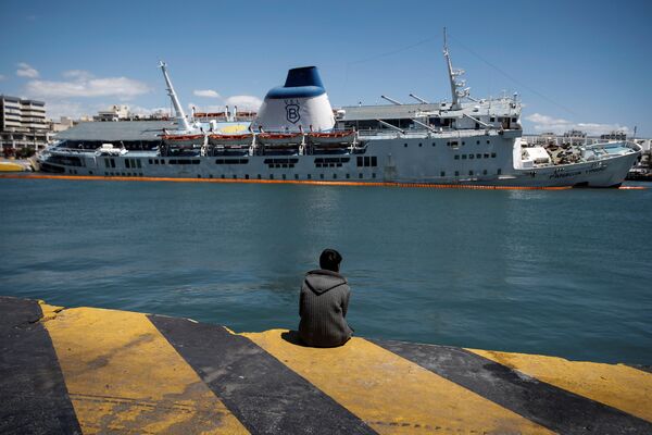 Um migrante olha para a balsa de passageiros inclinada Panagia Tinou que foi desmantelada no porto de Pireu, perto de Atenas, Grécia, 26 de abril de 2016 - Sputnik Brasil