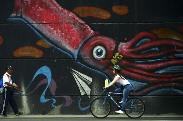 Uma colombiana vai em bicicleta diante de um grafite na cidade de Medellín. - Sputnik Brasil