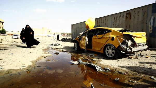 Iraqi women walk past a damaged car following a twin suicide bombing attack, claimed by the Islamic State (IS) group, in the southern Iraqi city of Samawah, situated deep in Iraq's Shiite heartland, on May 1, 2016 - Sputnik Brasil