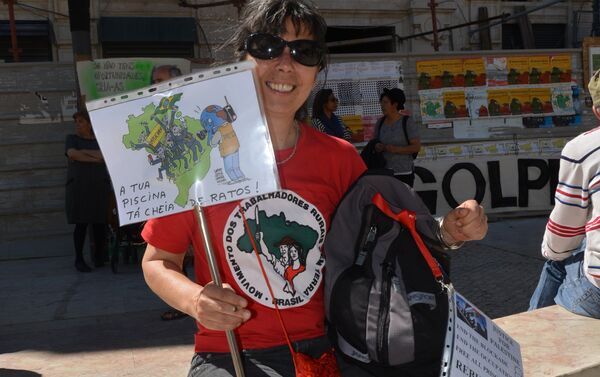 Uma manifestante vestindo camisa do Movimento dos Trabalhadores Rurais sem Terra mostra cartaz dizendo A tua piscina tá cheia de ratos em um ato com participação brasileira em 1 de maio de 2016 em Lisboa. No fundo da foto, umas pessoas mostram outro cartaz com as palavras Se não tens oportunidades, cria-as - Sputnik Brasil
