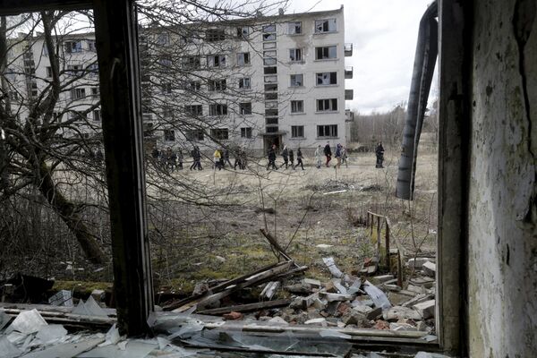 Um grupo de pessoas passam por um prédio abandonado da antiga estação soviética de radares perto da cidade de Skrunda, Letônia, 9 de abril, 2016 - Sputnik Brasil