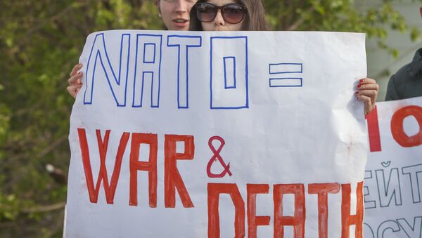 Activistas sosteniendo carteles anti-OTAN - Sputnik Brasil