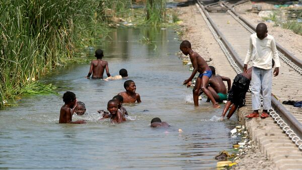 Crianças brincando em um reseratório de água ao lado de uma ferrovia em Luanda, Angola - Sputnik Brasil