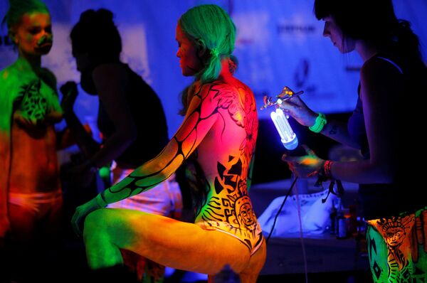 Um artista usa tinta para luz ultravioleta em uma modelo durante o Festival Mundial de Bodypainting em Portschach, no dia 1 de julho de 2016 - Sputnik Brasil
