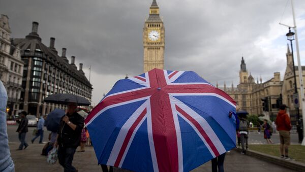 A pedestrian shelters from the rain beneath a Union flag themed umbrella as they walk near the Big Ben clock face and the Elizabeth Tower at the Houses of Parliament in central London on June 25, 2016 - Sputnik Brasil