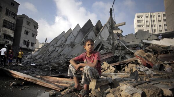 Menino palestiniano sentado sobre ruínas depois de bombardeio da Faixa de Gaza por Israel - Sputnik Brasil