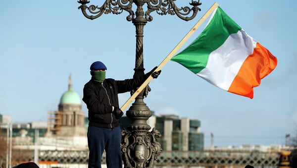 A demonstrator waves the national flag as people gather to protest against austerity policies and increases in water bills, according to local media, in central Dublin - Sputnik Brasil