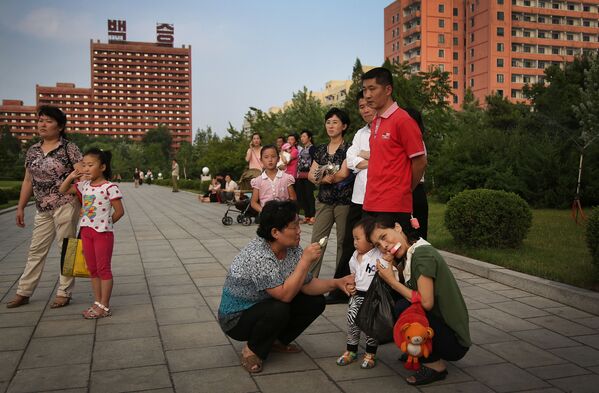 Mulheres e crianças norte-coreanas comem sorvetes assistindo uma festa de dança em massa em Pyongyang - Sputnik Brasil