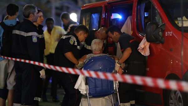 Rescue workers help an injured woman to get in a ambulance on July 15, 2016, after a truck drove into a crowd watching a fireworks display in the French Riviera town of Nice. - Sputnik Brasil