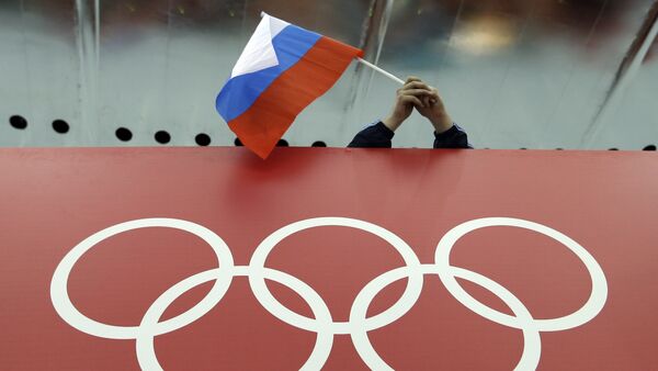 In this Feb. 18, 2014 file photo, a Russian skating fan holds the country's national flag over the Olympic rings before the start of the men's 10,000-meter speedskating race at Adler Arena Skating Center during the 2014 Winter Olympics in Sochi, Russia - Sputnik Brasil