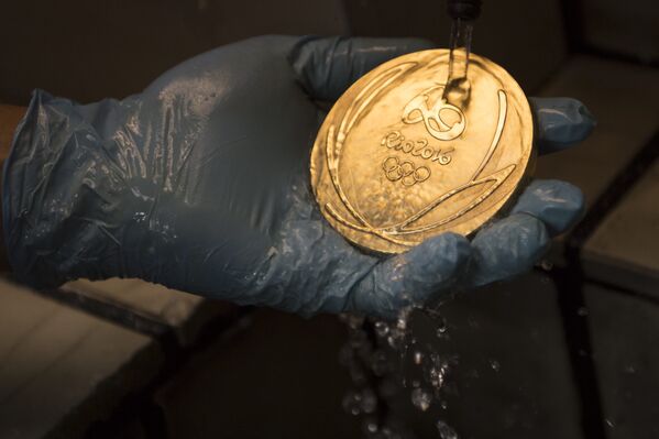 Um trabalhador limpa uma medalha de ouro dos Jogos Olímpicos no Rio 2016 após seu banho de ouro em uma fábrica de moeda no Rio de Janeiro - Sputnik Brasil