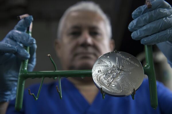 Um trabalhador prende uma medalha de prata dos Jogos Olímpicos no Rio 2016 após seu banho de ouro em uma fábrica de moeda no Rio de Janeiro - Sputnik Brasil