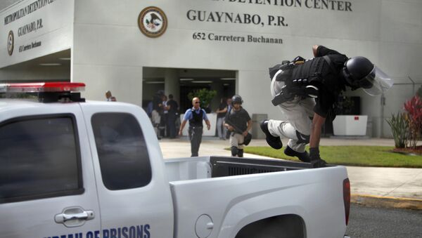 Um policial do batalhão de choque norte-americano salta de carro na frente do centro de detenção de Guaynabo de Porto Rico para acompanhar protesto contra a prisão de Óscar López Rivera - Sputnik Brasil