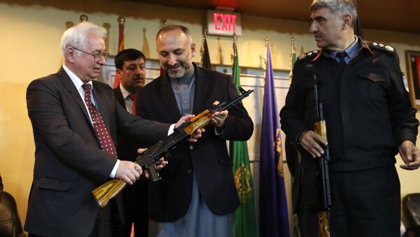 Russian Federation Ambassador, Alexander Mantytskiy, left, hands over an AK-47 to Afghan National Security Advisor, Mohammad Hanif Atmar, center, as the symbol of his country's military donation to the Afghan government, at Kabul International Airport, Wednesday, Feb. 24, 2016. - Sputnik Brasil