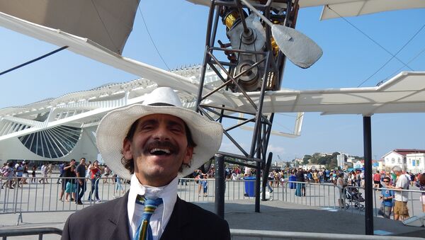 Homem fantasiado de Santos Dumont em frente à réplica do 14-Bis - Sputnik Brasil