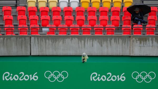 Um espectador senta-se sob o guarda-chuva na tribuna de uma quadra de tênis; partidas são atrasadas devido à chuva no Rio - Sputnik Brasil